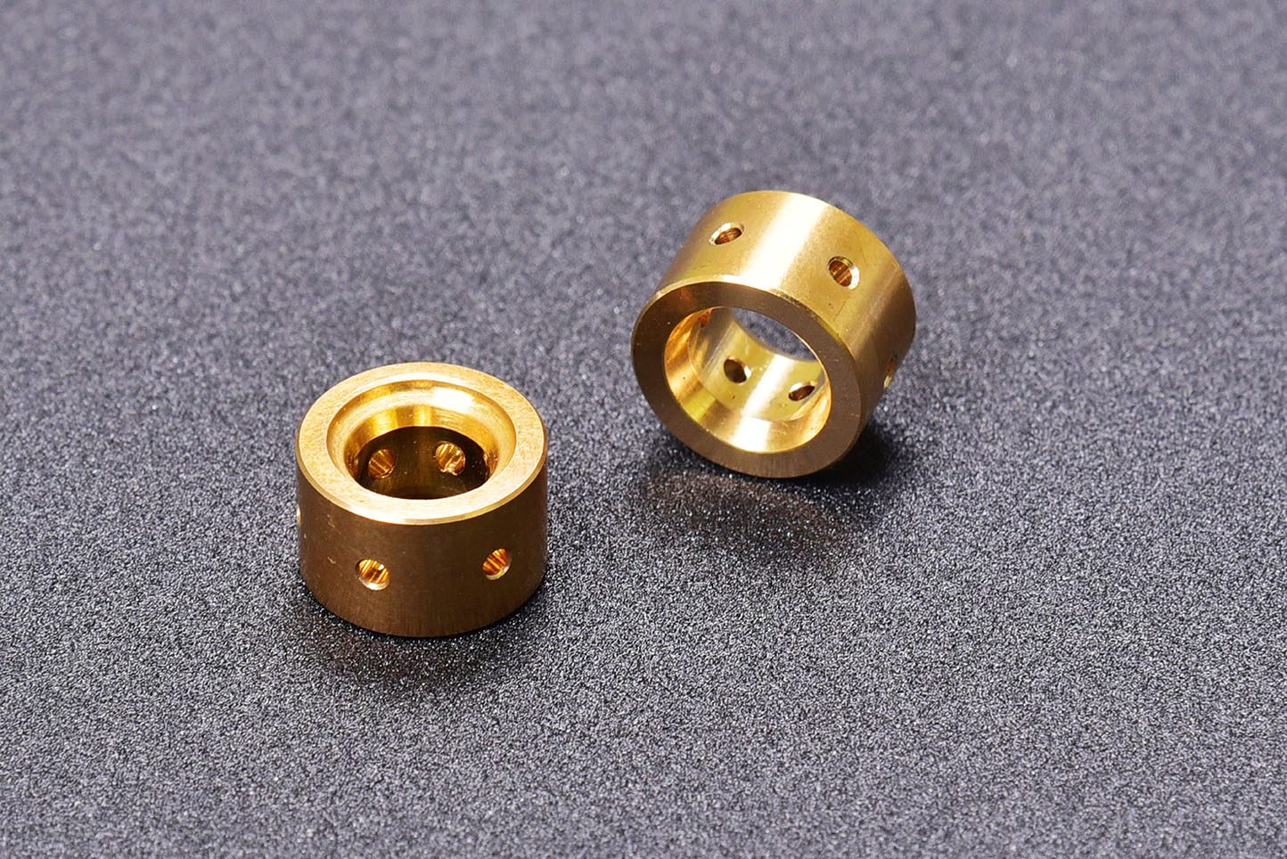 Two bronze bushes with cross-drilled oil holes, photographed on a grey ground