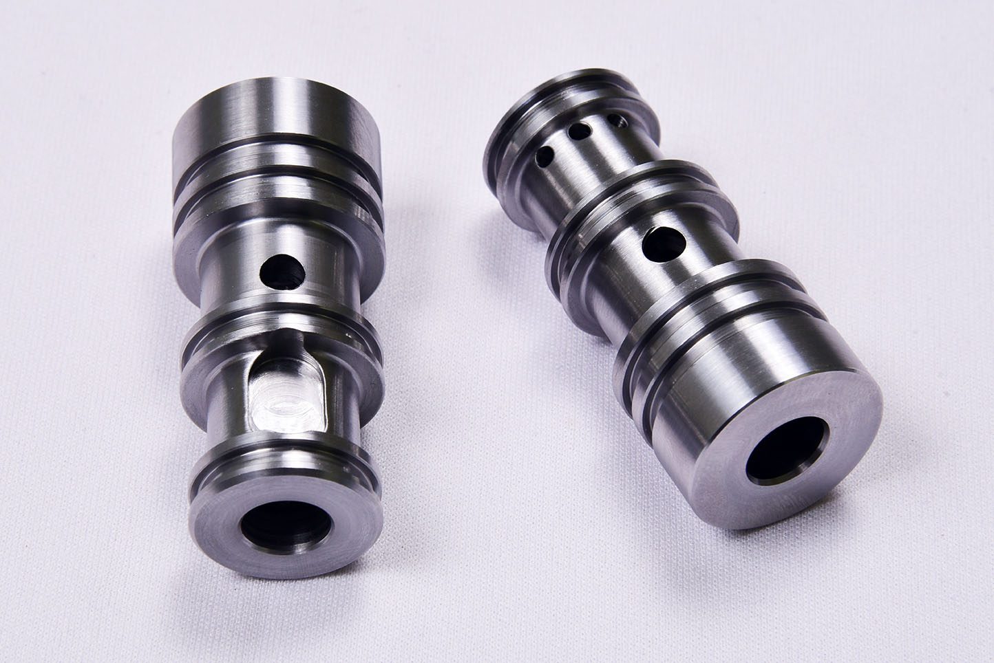 Two steel hydraulic cartridge valve bodies with turned lands and cross-drilled ports